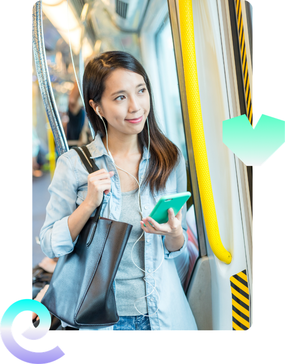 A woman on a train holding a mobile phone and smiling.